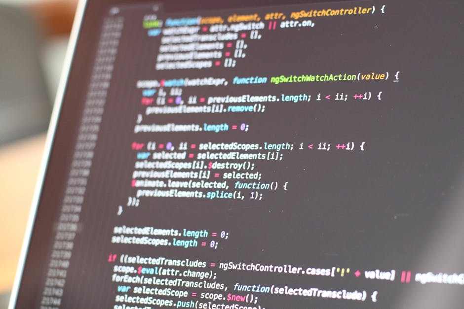 A close-up photograph of a computer screen displaying lines of colorful programming code with syntax highlighting, including keywords, functions, and variables in shades of blue, pink, green, and whit
