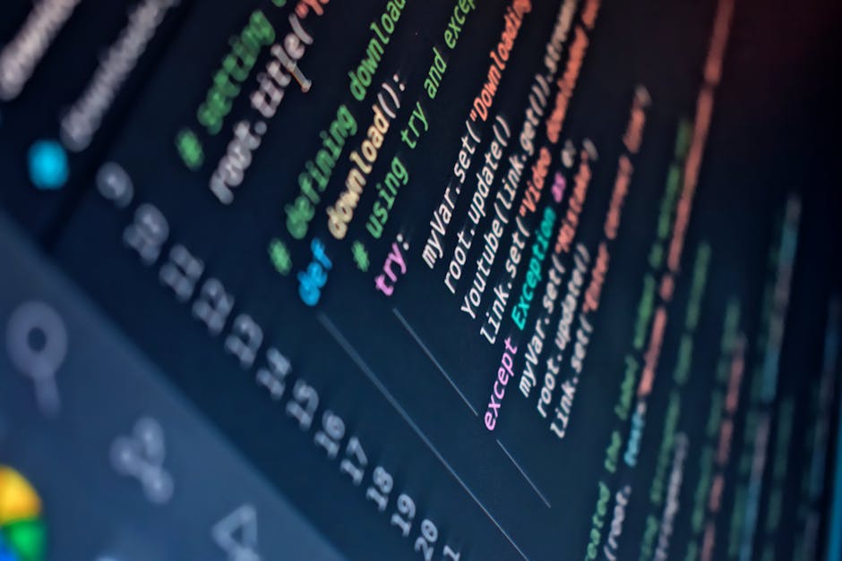 A close-up photograph of a computer screen displaying lines of colorful programming code with syntax highlighting, including keywords, functions, and variables in shades of blue, pink, green, and whit